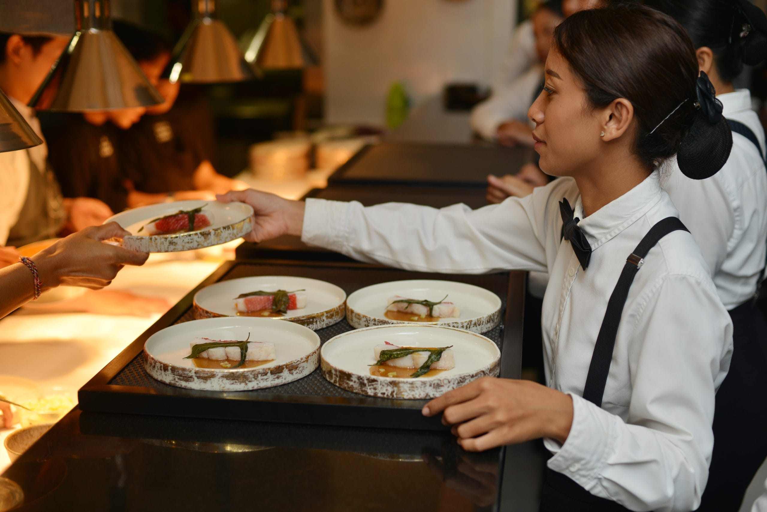 An event and party catering Bali staff member taking out plated meals for guests