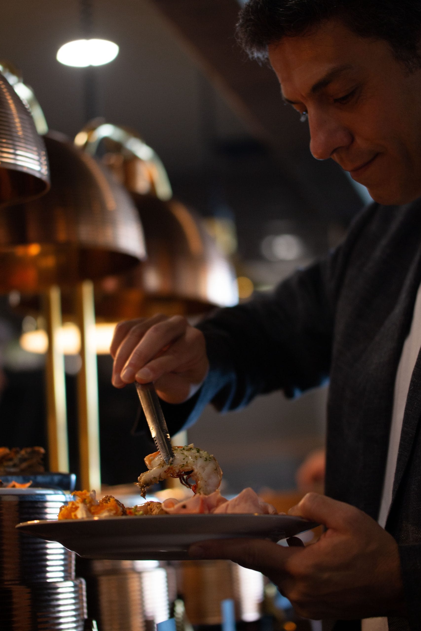 A person serving themselves seafood from a catered buffet at a private villa in Bali