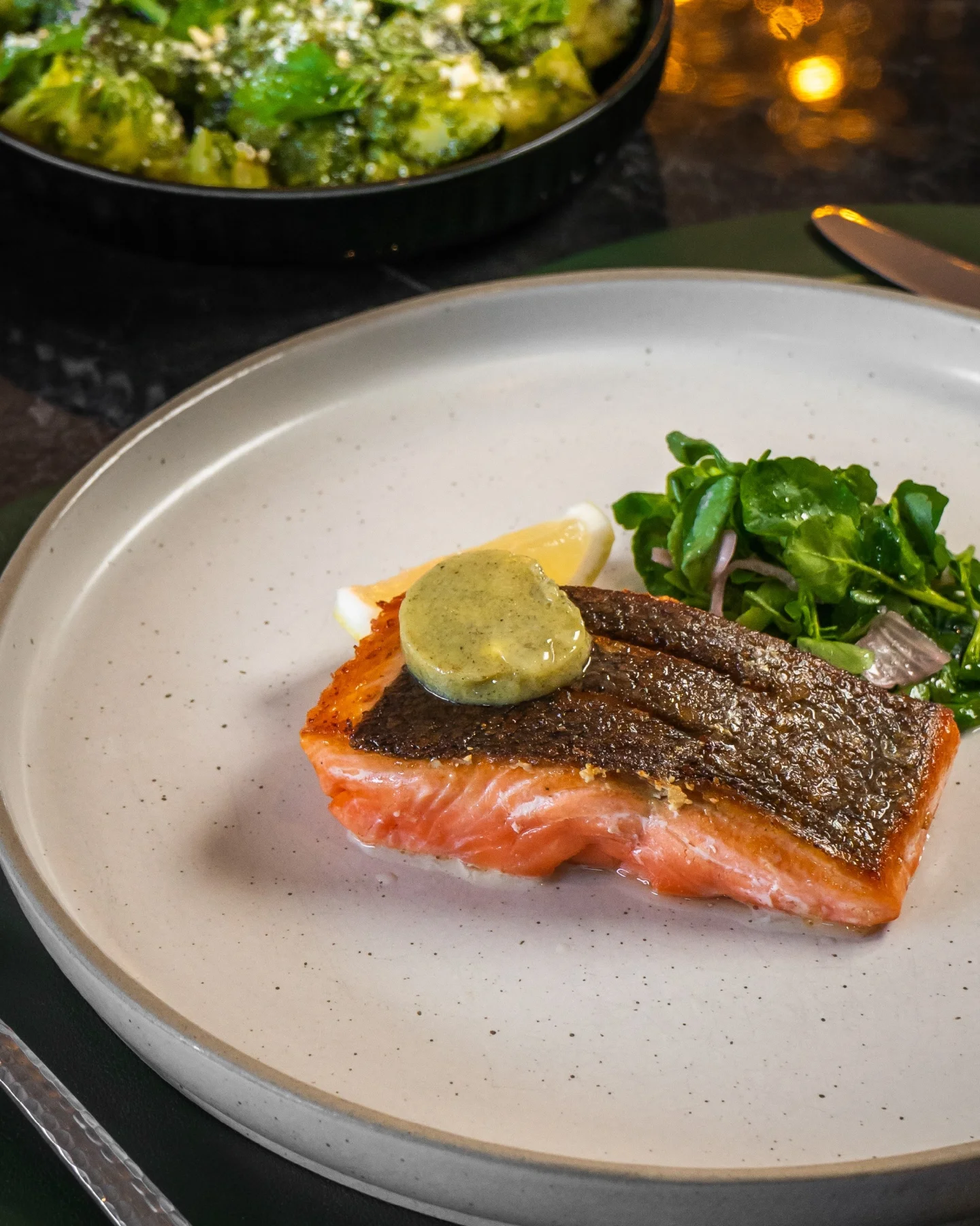 A dish of salmon with herbed butter and side salad